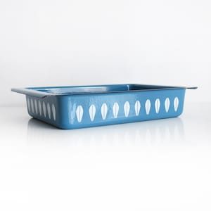 Puede incluir: Una fuente de horno rectangular de color azul con un acabado esmaltado brillante. Los lados exteriores presentan un patrón repetitivo de motivos blancos en forma de hoja orientados verticalmente. La fuente tiene un borde ancho y plano.