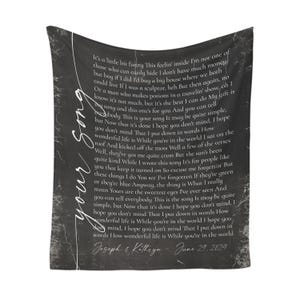 May include: A black throw blanket with white script text. The text includes song lyrics and the words "your song." The bottom of the blanket has the names "Joseph & Kathryn" and the date "June 29, 2024."