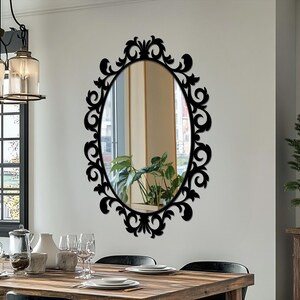 Specchio da parete ovale nero decorato, con cornice a volute in stile vintage