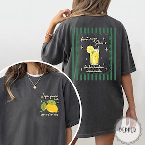 May include: Dark gray t-shirt with a lemon graphic and the text "Life gave me some lemons" on the front. The back features a lemonade graphic with the text "but my Jesus he be makin' lemonade".