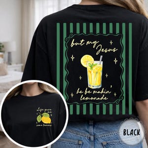 May include: Black t-shirt with a lemonade graphic. The back features a green striped border with the text "but my Jesus he be makin' lemonade." A smaller image on the front says "Life gave me some lemons."