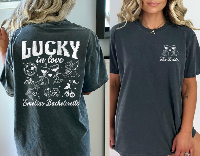 May include: Two dark gray t-shirts. One features the text "LUCKY in love" with illustrations of a disco ball, wine glasses, and dice. The other shirt has a wine glass design and the text "The Bride".