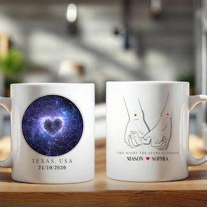 Könnte beinhalten: Weiße Keramik-Tasse mit einem herzförmigen Sternbild-Design und dem Text "TEXAS, USA 21/10/2020". Die andere Seite zeigt eine Strichzeichnung von Händen, die sich halten, mit dem Text "THE NIGHT THE STARS ALIGNED MASON SOPHIA".