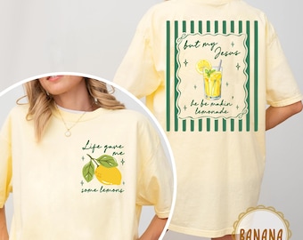 May include: A light yellow t-shirt with the text "Life gave me some lemons" and a lemon graphic on the front. The back features the text "but my Jesus he be makin' lemonade" with a lemonade graphic. The shirt has green and white stripes.
