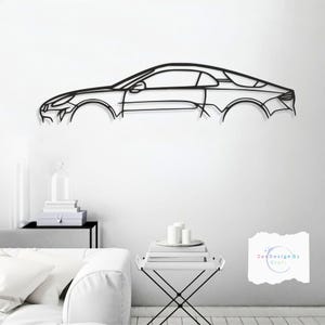 May include: A black metal wall art piece depicting the outline of a sports car. The car's design is minimalist, with clean lines and a sleek profile. The artwork is mounted on a white wall, creating a striking contrast.