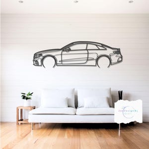 May include: A metal wall art piece depicting a car's outline, mounted on a white wall above a white sofa. The car is a coupe style, with visible details like the wheels, headlights, and side profile. The artwork adds a modern touch to the room.