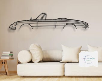 May include: Black metal outline of a convertible car mounted on a white wall above a white couch with two pillows. The text "Zen Design By Craft" is visible in the lower right corner of the image.