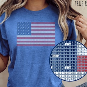 May include: A blue t-shirt with a graphic of the American flag on the front. The flag design features red and white stripes and a field of blue with white stars. The text "HEATHER TRUE ROYAL" is printed at the top.