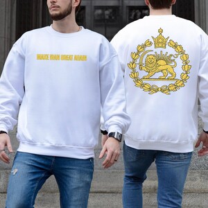 May include: White sweatshirt with the text "MAKE IRAN GREAT AGAIN" in gold lettering on the front. The back features a gold emblem with a lion, crown, and wreath design. The sweatshirt is paired with blue jeans.
