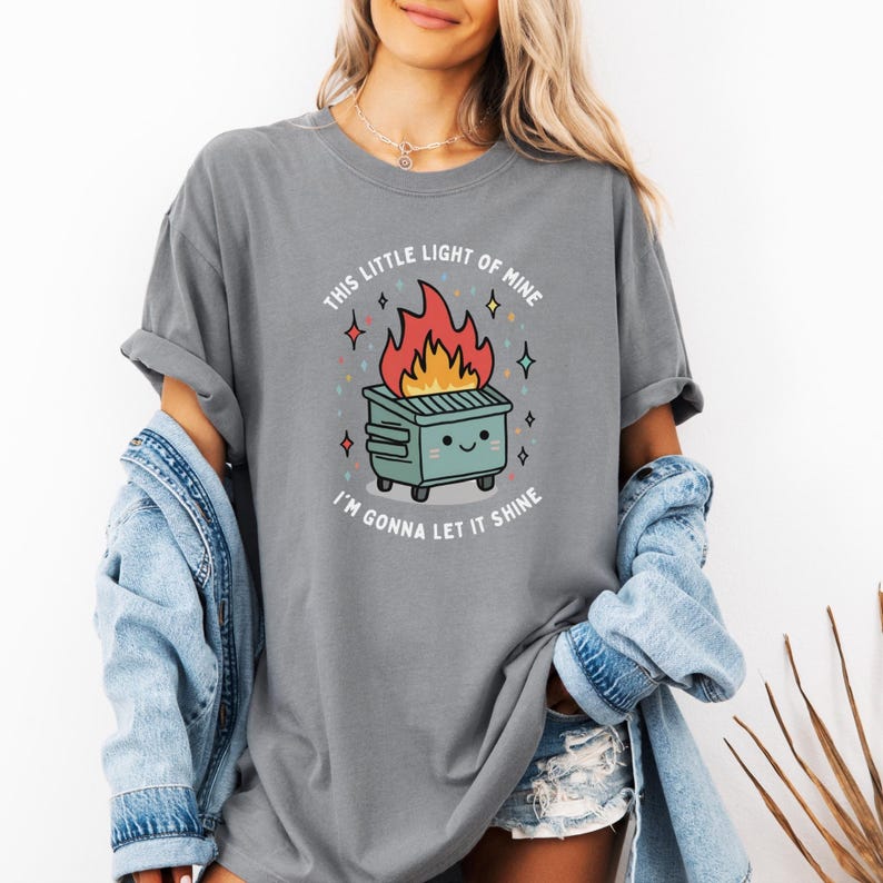 May include: Gray t-shirt with a graphic of a cartoon dumpster on fire with the text "This little light of mine I'm gonna let it shine".