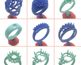 May include: Nine different wax ring designs for jewelry making. The rings are made of blue and green wax and are displayed on red stands.