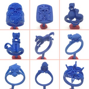 May include: Nine different blue wax ring molds, each featuring a unique design. The designs include a skull, a cat, a horse, a frog, a turtle, a monkey, and a flower. The molds are all made of a smooth, blue wax.