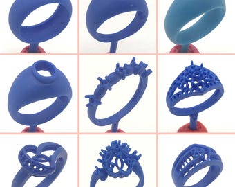 May include: Nine different blue wax ring molds for jewelry making. The molds are on display on red stands. Some of the molds have intricate designs, while others are simple bands.