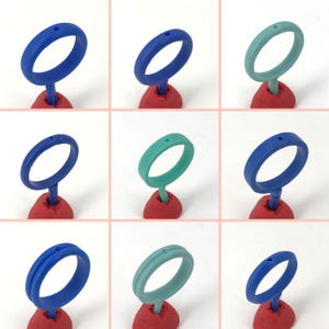 May include: Three sets of wax rings, one set in blue, one in teal, and one in a lighter shade of teal. Each set has three rings, one with a smooth surface, one with a single groove, and one with a double groove.
