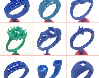 May include: Nine different blue and green plastic ring molds for jewelry making. The molds are on small red stands.