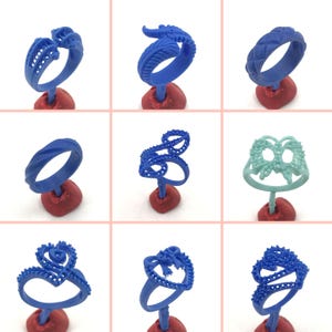 May include: Nine different blue wax ring molds on red bases. The molds are in various shapes, including hearts, swirls, and geometric designs.