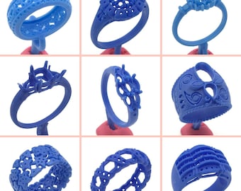 May include: Nine blue plastic ring molds for jewelry making. The molds are on small pink stands. The molds are different designs, some with intricate details.