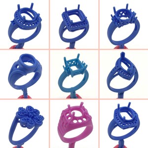 May include: Nine different ring settings for jewelry making. The settings are made of blue and pink wax and are displayed on a white background.