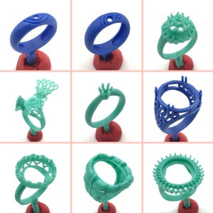 May include: Nine different 3D printed wax ring models in blue and green on red stands. The rings are for making jewelry.