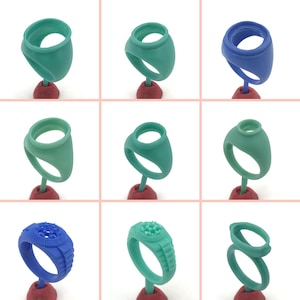 May include: A grid of nine ring molds in various shades of green and blue. The molds are mounted on red stands. Some rings have a smooth design, while others have textured details. The rings are likely for jewelry making.