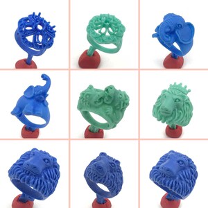 Puede incluir: Nueve diseños diferentes de anillos de cera para la fabricación de joyas. Los anillos presentan varios diseños de animales y flores en azul y verde.