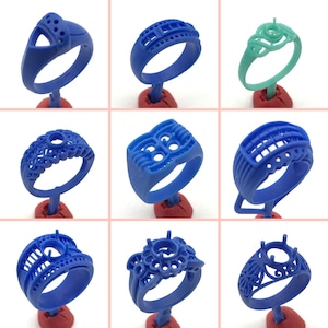 May include: Nine different blue and green wax ring moulds for jewellery making. The moulds are on display on small red stands.