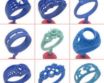 May include: Nine different blue and turquoise wax ring models for jewelry making. The rings are displayed on red and green stands.