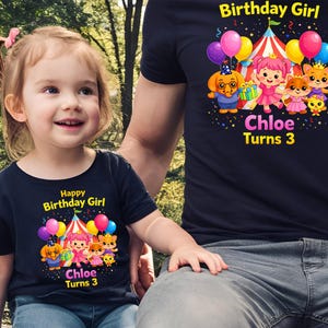 Op de afbeelding: Twee marineblauwe T-shirts met een kleurrijk verjaardagsontwerp. Het ontwerp bevat een circustent, ballonnen en stripfiguren. De tekst op de shirts luidt "Happy Birthday Girl" en "Chloe Turns 3".