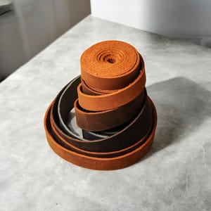 May include: A stack of brown leather strips, rolled up and ready for crafting projects.