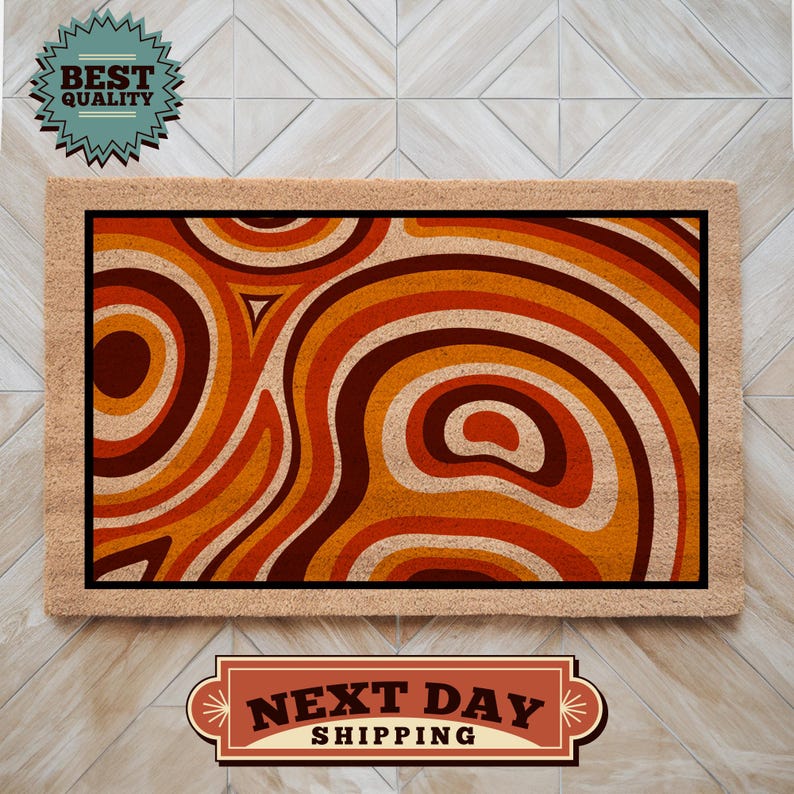 May include: A brown doormat with a geometric pattern of orange, red, and brown swirls. The doormat has a black border and a tan backing.