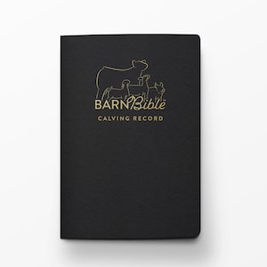 May include: A black notebook with gold lettering and a line drawing of a cow and calves. The text on the cover reads "BARN Bible CALVING RECORD". The notebook is closed and has a textured surface.