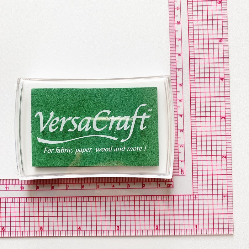 Pode incluir: Uma almofada de tinta verde com um r&oacute;tulo branco que diz "VersaCraft&trade; Para tecido, papel, madeira e muito mais!"