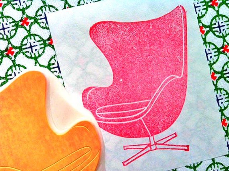 A hand carved rubber stamp of Egg chair, shown with a stamped example in red on white paper.