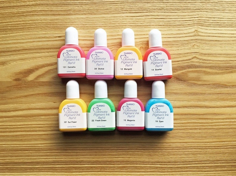 以下が含まれることがあります： ツキノ Ultimate Pigment Ink Refill の小さなボトルが 8 本。カメリア、オーキッド、マリーゴールド、スカーレット、サンフラワー、フレッシュグリーン、マゼンタ、シアンなど、さまざまな色があります。