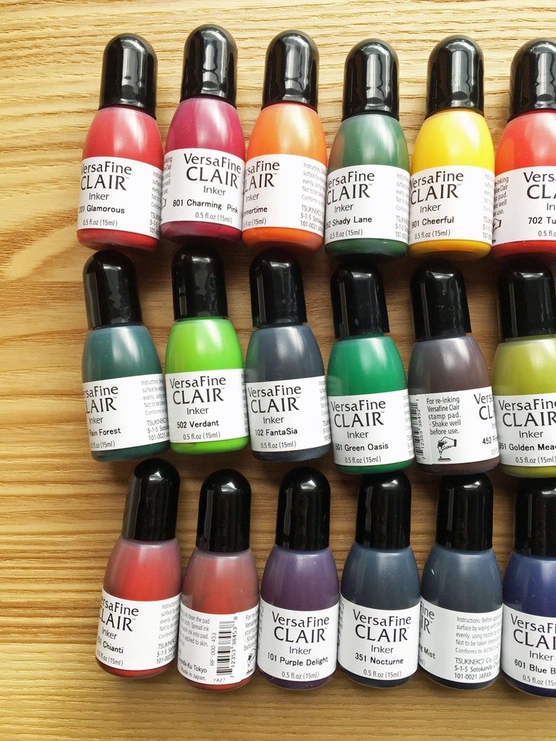 K&ouml;nnte beinhalten: Eine Sammlung von 14 kleinen Flaschen VersaFine Clair Tinte in verschiedenen Farben, darunter Gr&uuml;n, Rot, Blau, Lila und Gold. Jede Flasche ist mit dem Markennamen, der Tintenfarbe und der Gr&ouml;&szlig;e (0,5 fl oz / 15 ml) gekennzeichnet.