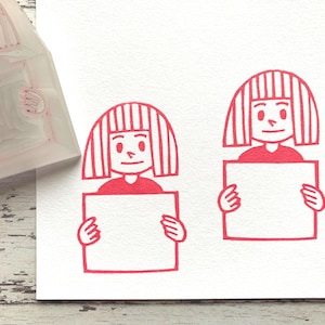 メッセージボードのゴム印を持った女の子、カード作り用の手彫りのスタンプ、クリエイターへのギフト