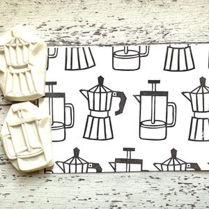 May include: Two off-white coffee pot stamps next to a white card with a black and white coffee pot pattern. The stamps are detailed with the shape of a coffee pot. The card has various coffee pot illustrations.