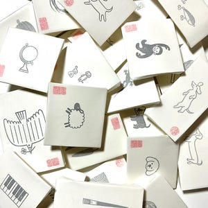 A sample image of packagings for hand carved rubber stamps - wrapped with glassine paper and a stamped example card.
