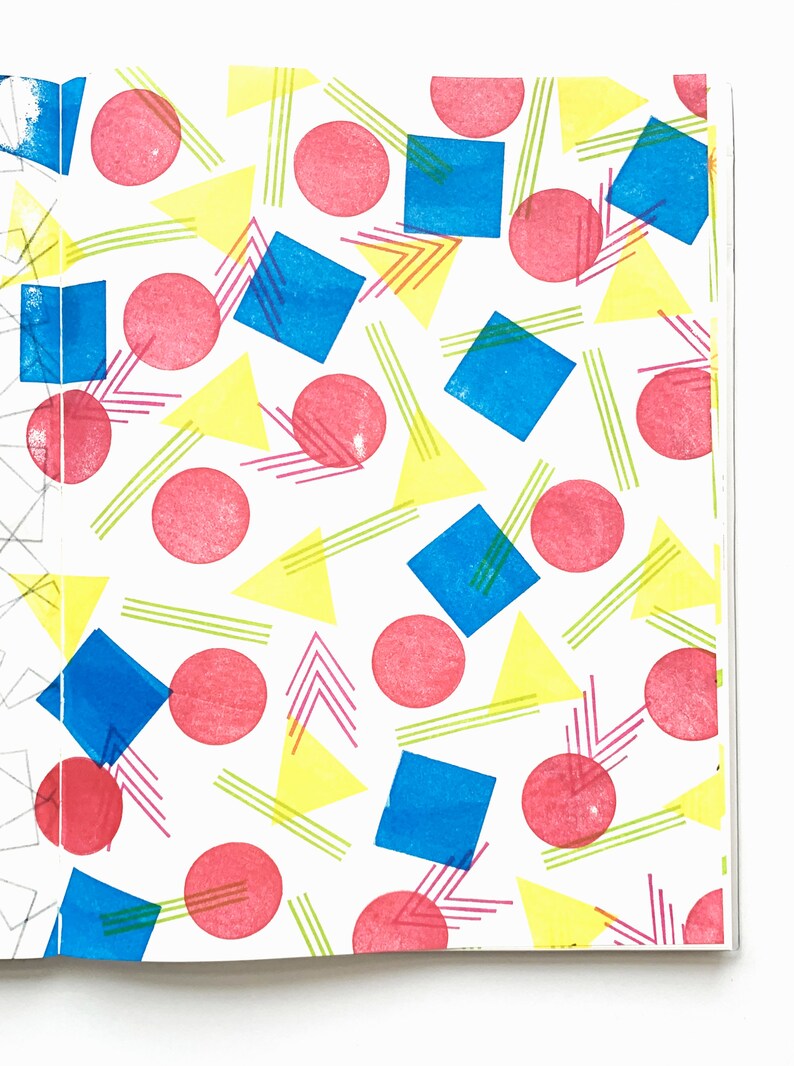 May include: A white background is covered with a repeating pattern of pink circles, blue squares, yellow triangles, and green and pink lines. The shapes are arranged in a playful, geometric design.