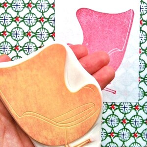 A hand carved rubber stamp of Egg chair, shown with a stamped example in red on white paper. The stamp is held in the hand.