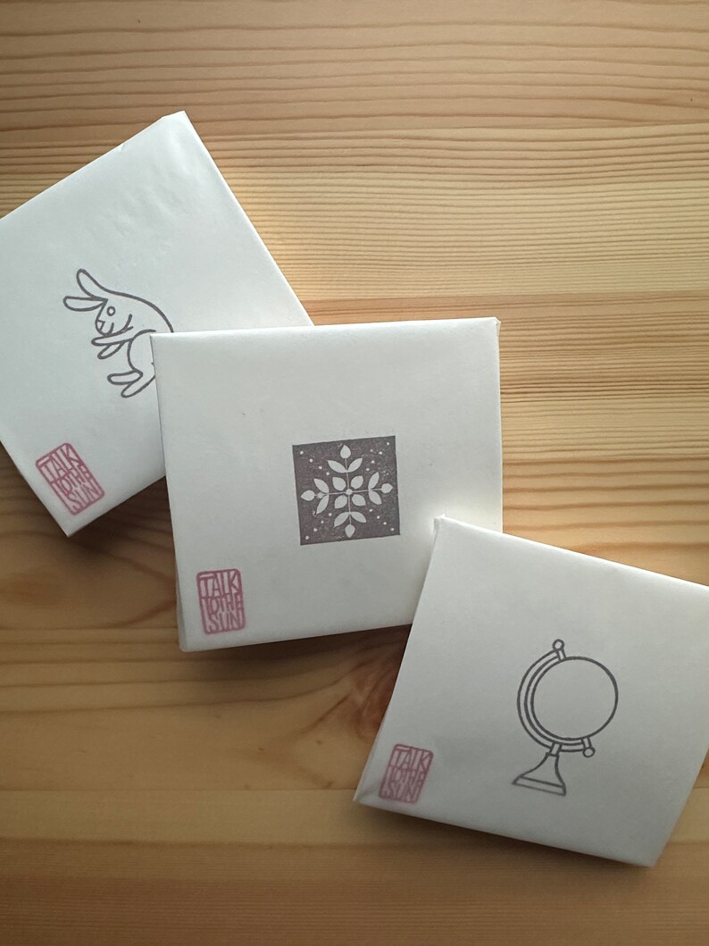 A sample image of packagings for hand carved rubber stamps - wrapped with glassine paper and a stamped example card.