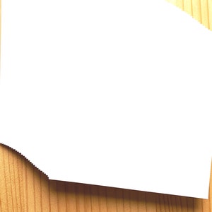 May include: A stack of white paper on a wooden surface.