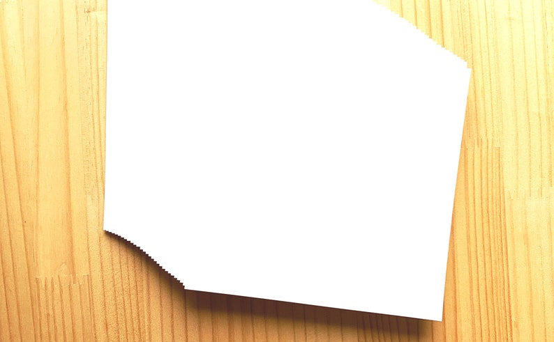 May include: A stack of white paper on a wooden surface.