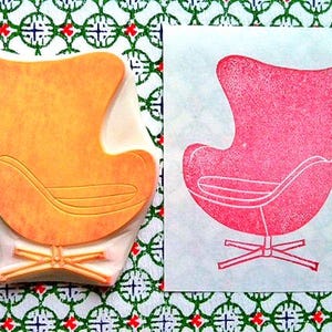 A hand carved rubber stamp of Egg chair, shown with a stamped example in red on white paper.