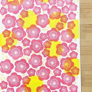 A sample image of pattern design using hand carved rubber stamps available in the shop to share ideas for art and craft projects. This one shows plum blossoms in red and yellow circles and little flowers on the background.
