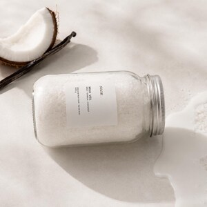 Jar of pale creamy Milk Veil bath soak made with mineral salts, milk powder, coconut, and vanilla fragrance