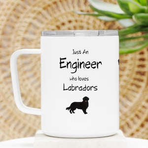May include: White stainless steel travel mug with a black handle. The mug has a black silhouette of a Labrador Retriever and the text "Just An Engineer who loves Labradors".