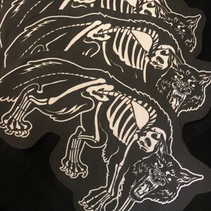 May include: Four black and white iron-on patches featuring a skeletal wolf design. The wolf is depicted in a snarling pose with its teeth bared. The patches are ideal for adding a touch of edgy style to clothing, bags, or other accessories.