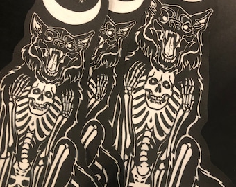 Puede incluir: Tres parches bordados en blanco y negro de un lobo con una calavera dentro de su cuerpo, sentado con una luna creciente sobre su cabeza.