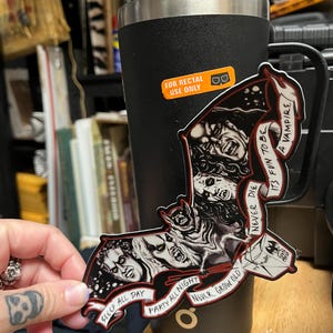 May include: A black and red bat-shaped sticker featuring vampire faces and the phrases "Sleep All Day", "Party All Night", and "Never Grow Old". The sticker is held near a black tumbler with a "For Rectal Use Only" sticker.